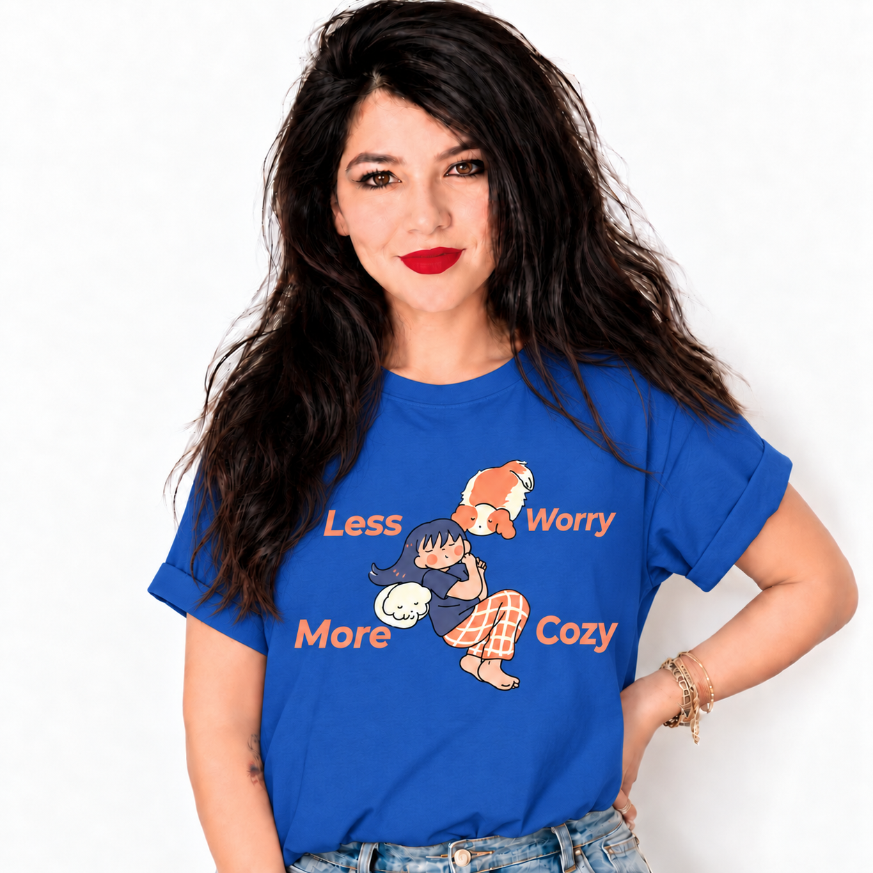 A woman with long dark hair and red lipstick wearing a blue graphic t-shirt with a cartoon character and the text 'Less Worry More Cozy'.