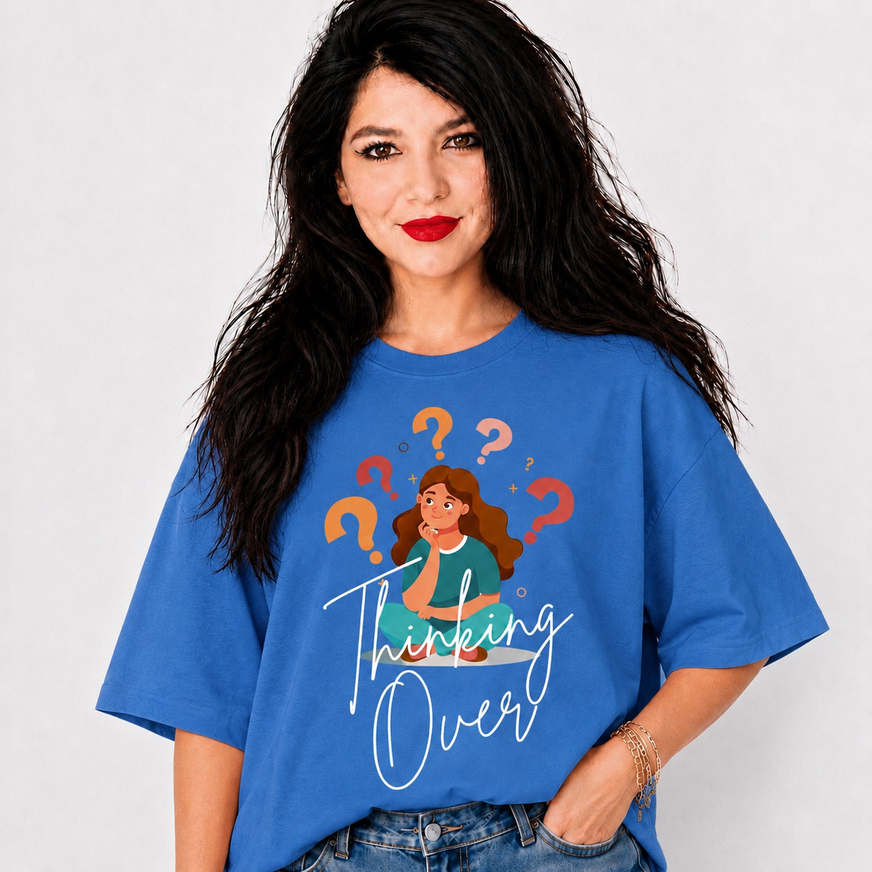 A woman with long black hair wearing a blue graphic t-shirt that reads 'Thinking Over' with an illustration of a woman surrounded by question marks, set against a plain light gray background.